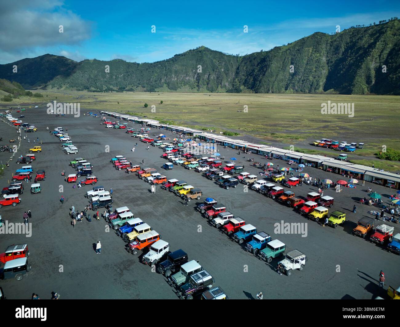 Old Toyota Landcruisers for transporting tourists, on Segara Wedi (sand ocean) below Mt Bromo Volcano (Gunung Bromo) East Java, Indonesia - aerial Stock Photo
