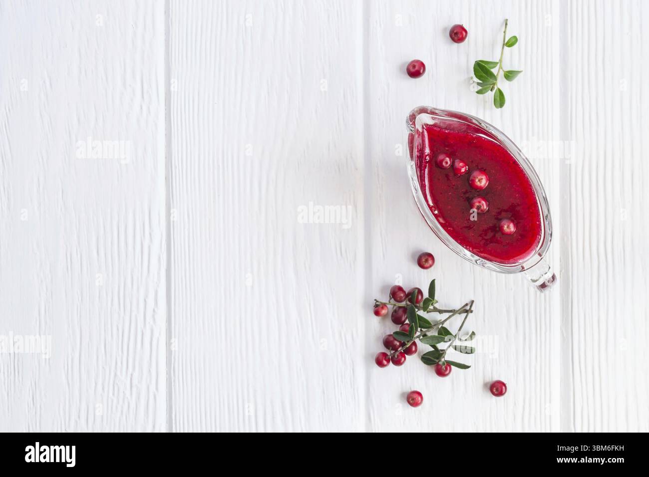 Fresh Lingonberry sauce in a gravy boat On a white wooden background. Top view with copy space Stock Photo