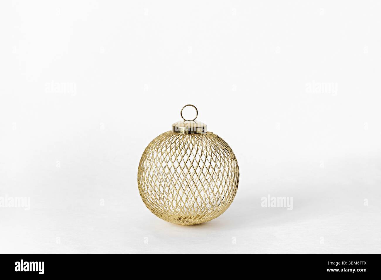 Golden Metallkugel Nahaufnahme auf weissem Hintergrund. Weihnachten nachhaltig Bauble. Konzept fuer Weihnachten oder Neujahr Stock Photo