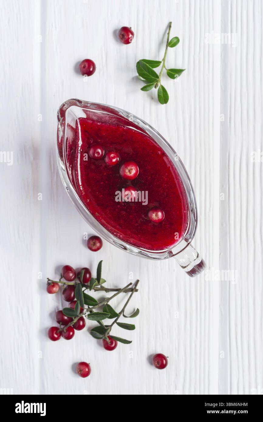 Fresh Lingonberry sauce in a gravy boat on a white wooden background Stock Photo