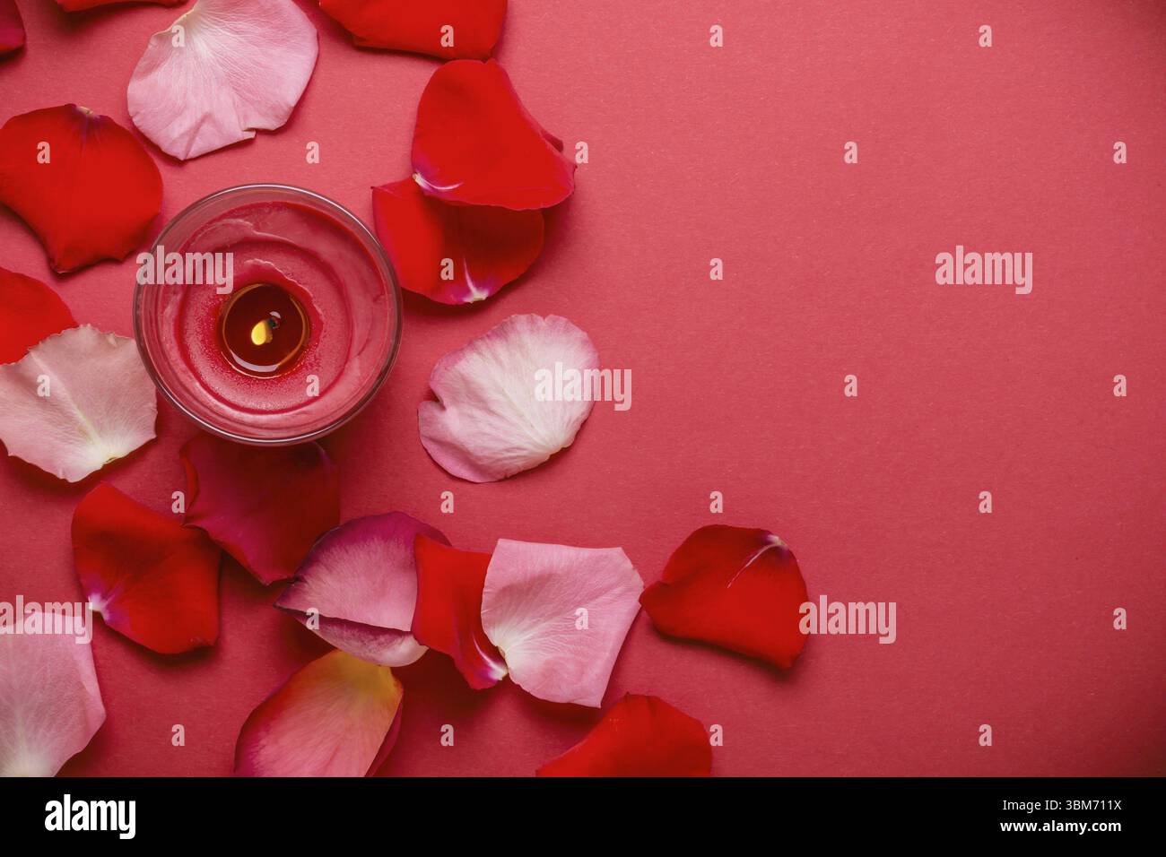 Candle and rose petals on a red background Stock Photo - Alamy