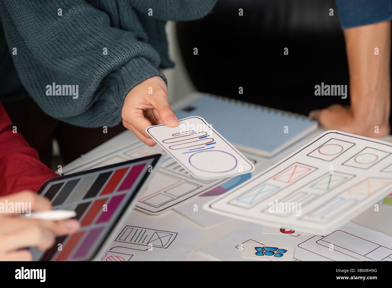 User Experience Design and Presentation. Designers showcasing mobile user interface layouts while discussing project ideas. Stock Photo