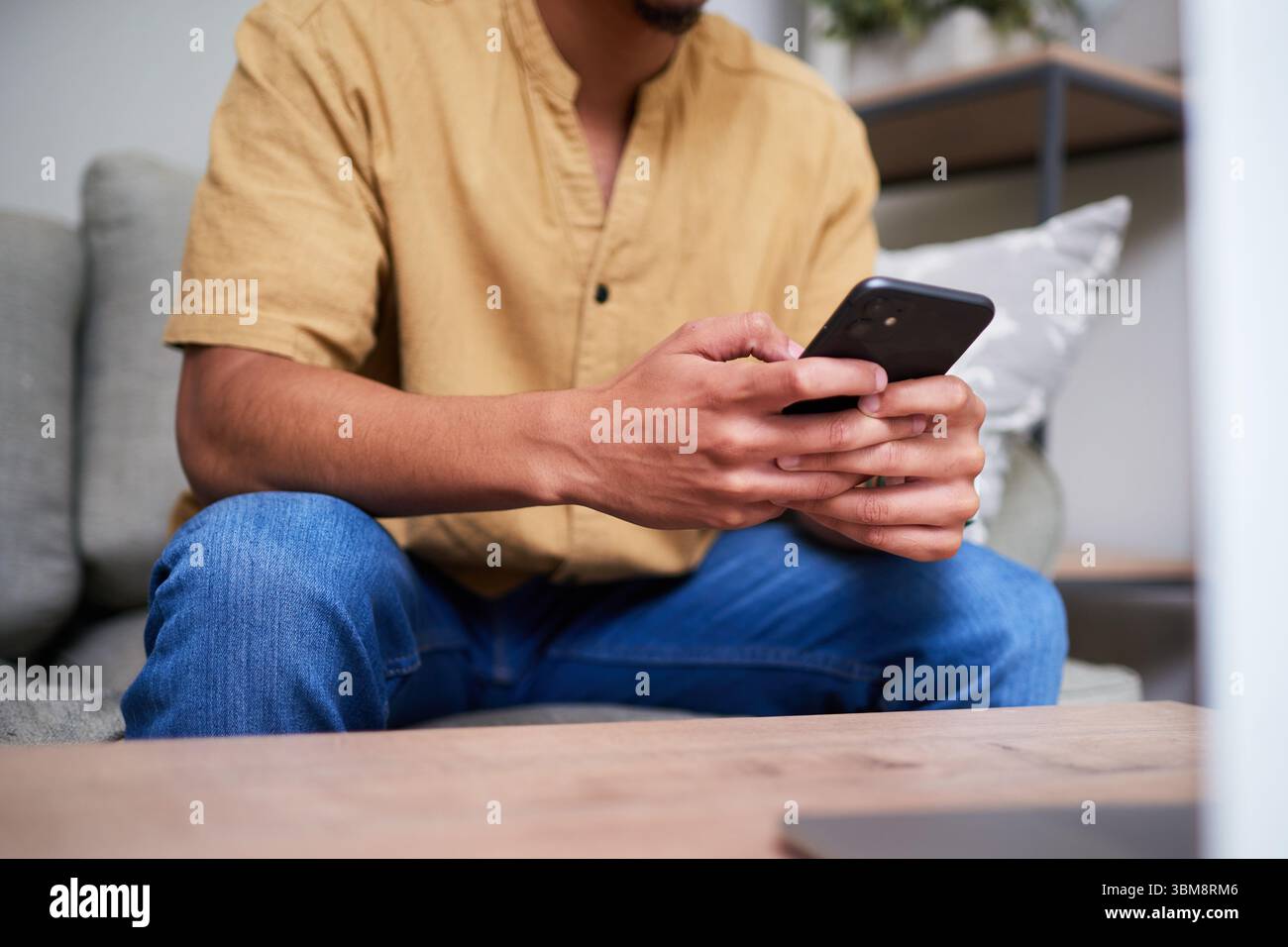 Man Relaxing at Home While Using Smartphone for Communication Stock Photo