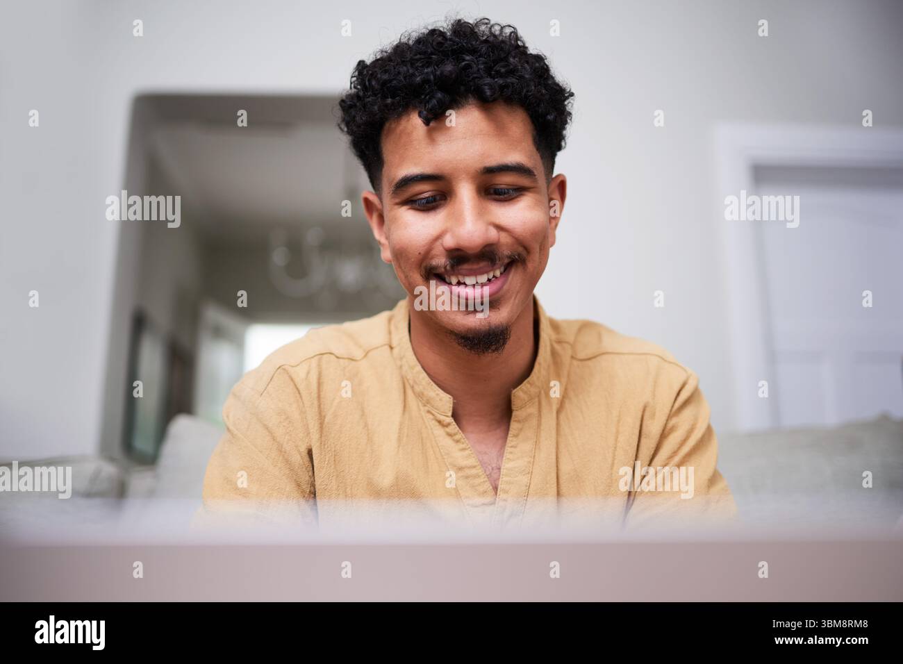 Smiling Man Working From Home With a Positive Attitude While Using a Laptop Stock Photo