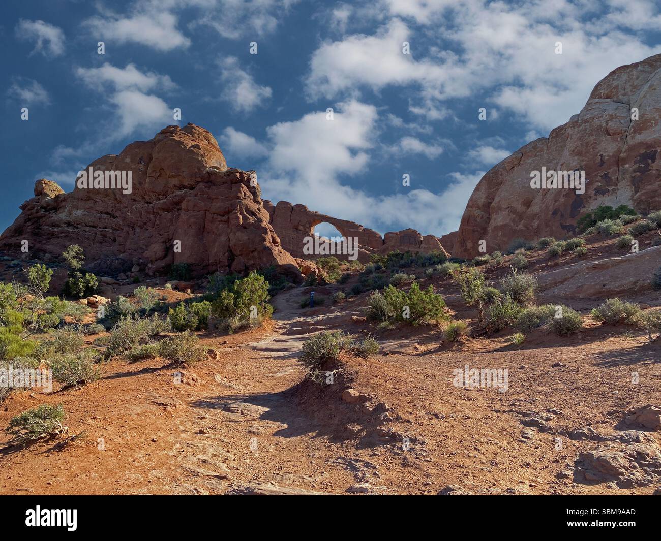 A desert landscape in Arches National Park with rock formations, an arch and scrub brush on the Skyline Arch Trail, Utah - Smartphone Captured Stock Image