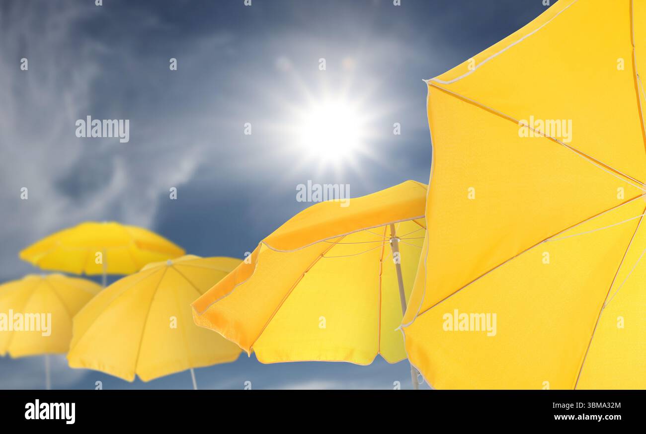 Yellow beach umbrellas against blue sky on sunny day Stock Photo