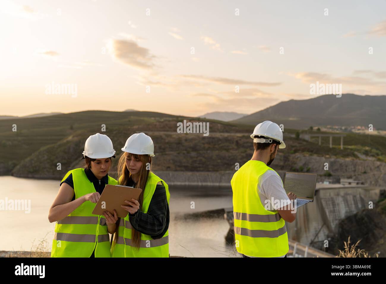 Engineers using digital tablet and laptop at dam construction site Stock Photo