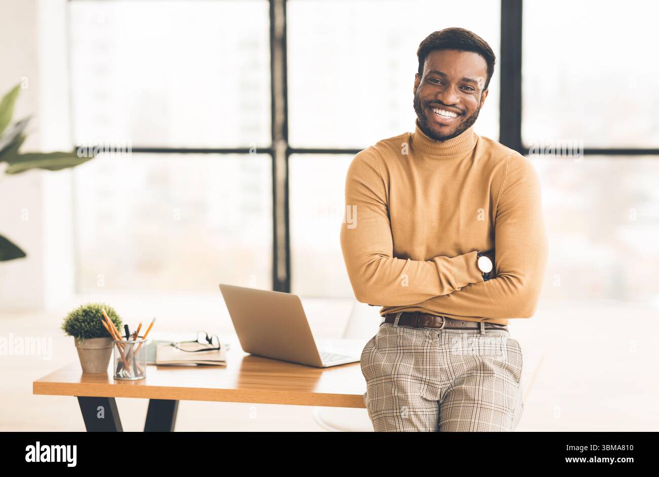 Successful black man sitting on desk at office Stock Photo