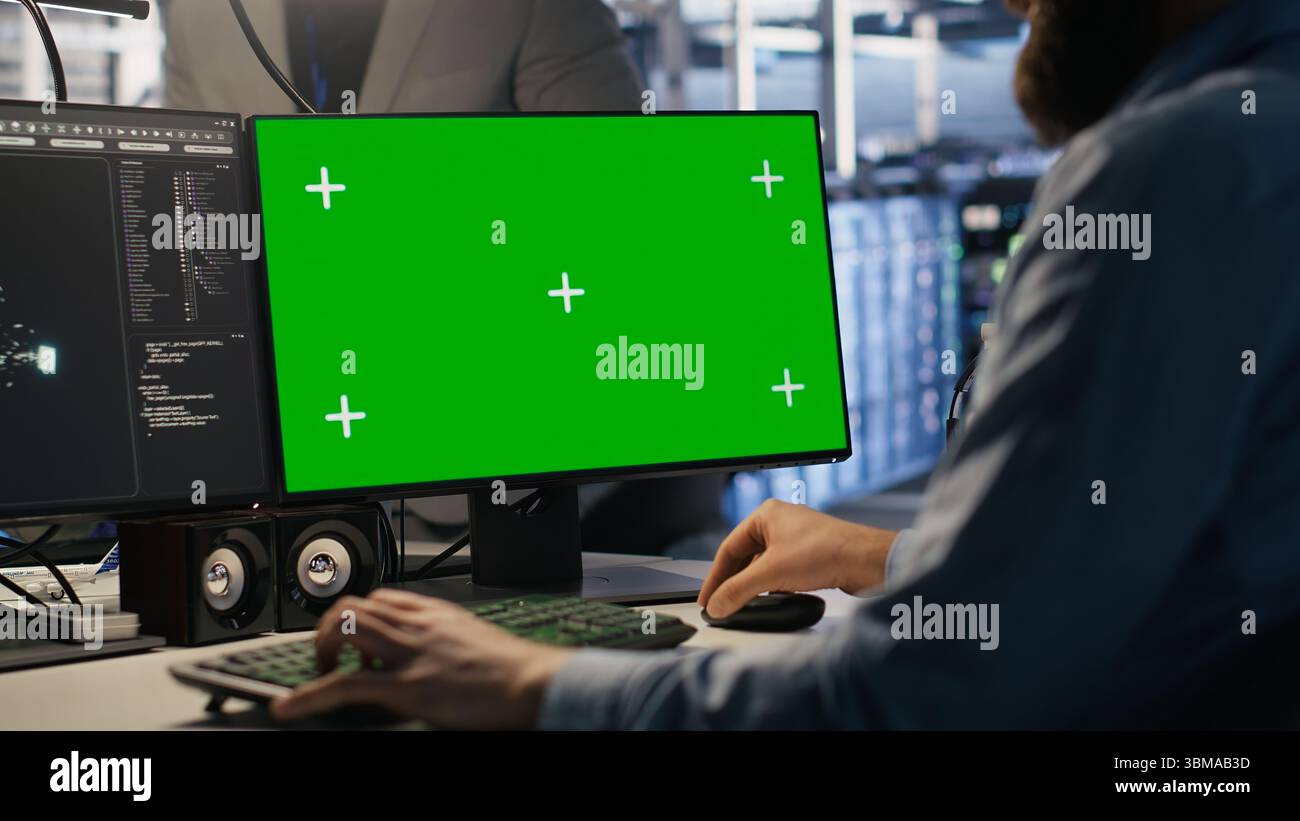 Engineer using green screen mockup PC in data center to update servers tech, configuring equipment using software tools. Server room worker reviewing hardware analytics on chroma key PC, camera A Stock Photo