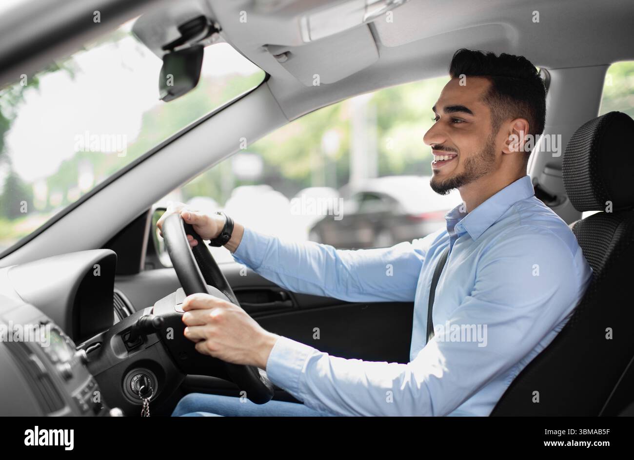 Joyful arabic guy driving nice auto, side view Stock Photo
