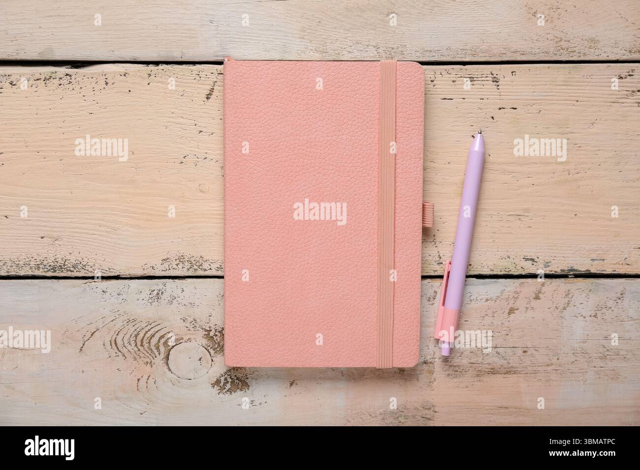 Composition with pink notebook and pen on beige wooden background, closeup Stock Photo