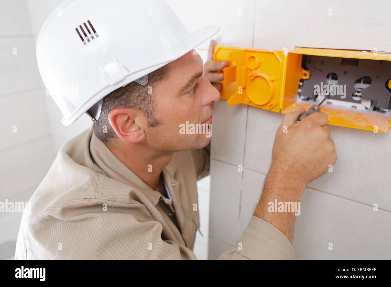 electrician installing electrical socket casing in bathroom Stock Photo