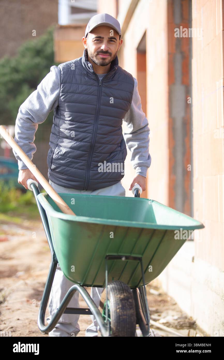 young builder pushing a wheelbarrow Stock Photo