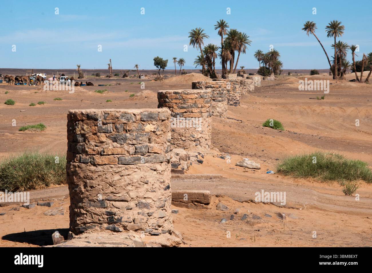 A line of stone wells stretches across the desert outside the Saharan oasis township of Merzouga Stock Photo