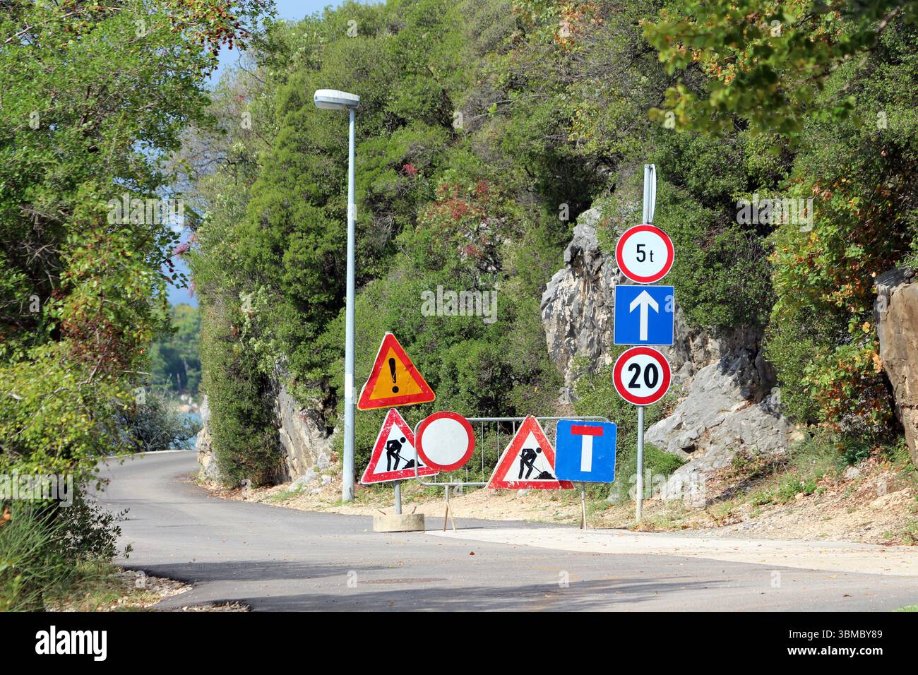 Rocky Rpad Sign Narrow paved road curves through rocky forest, marked with numerous ...