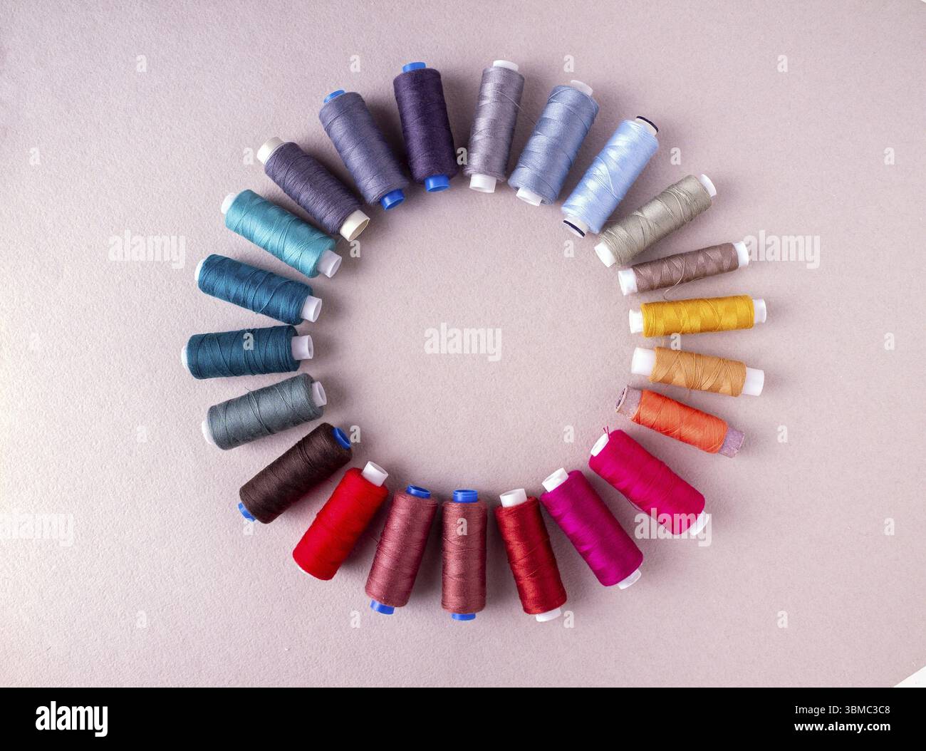 Spools with multi-colored threads form a circle on a light background, copy space Stock Photo