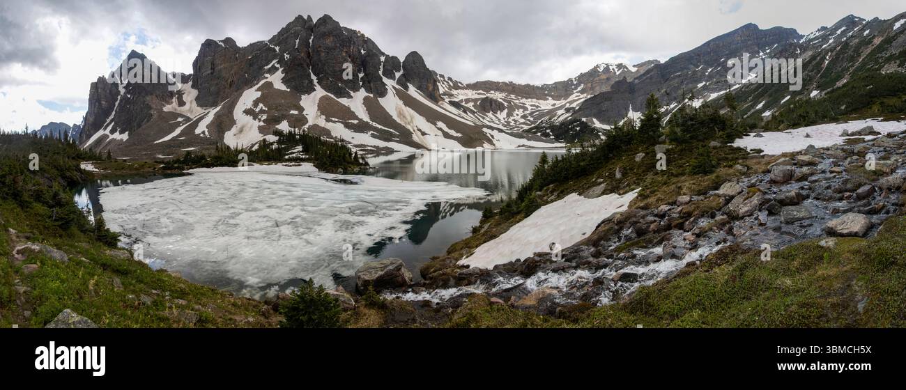 A picturesque alpine scene features a serene lake surrounded by snow ...
