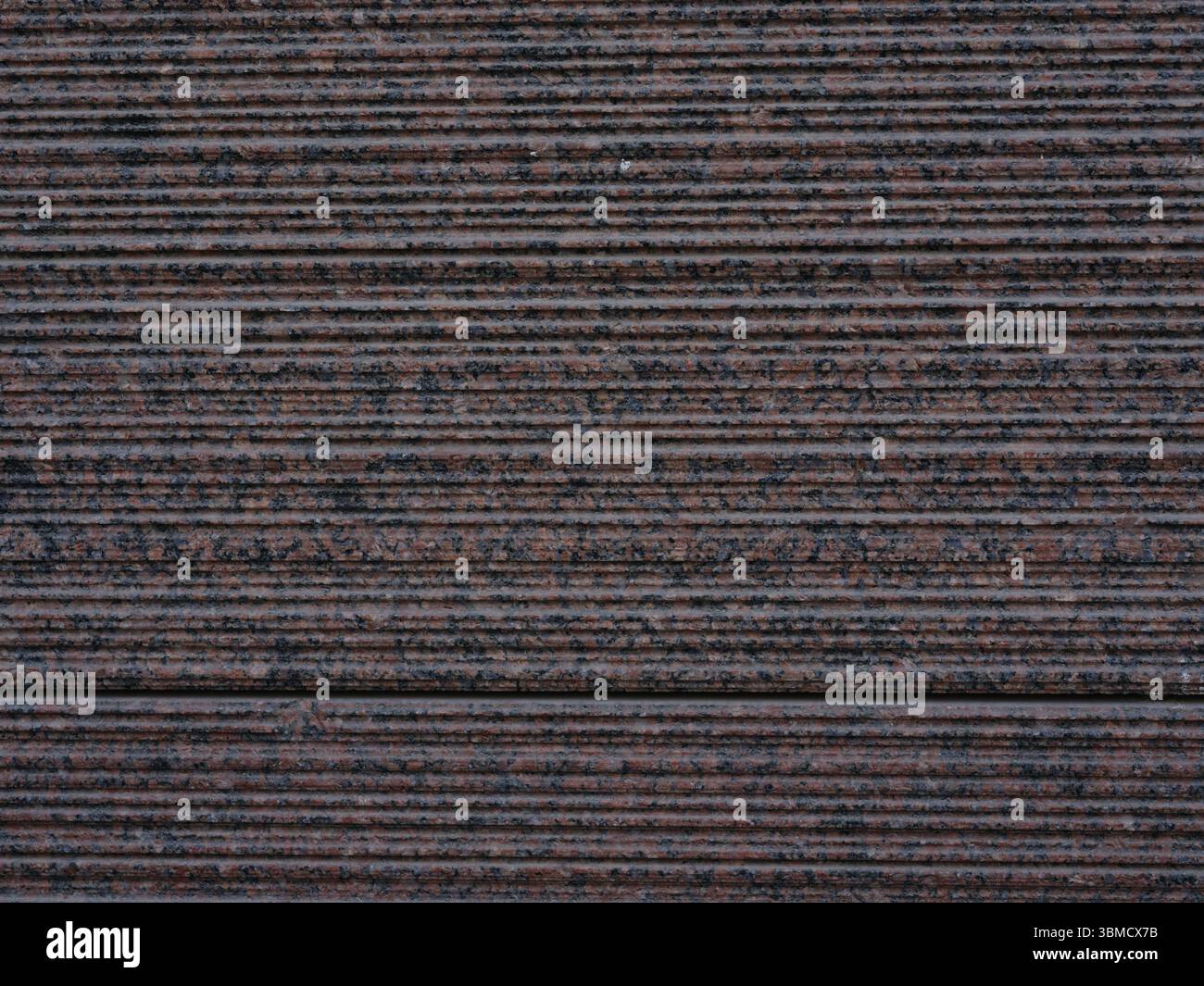Close-up surface of striped and ribbed red and black facing granite ...
