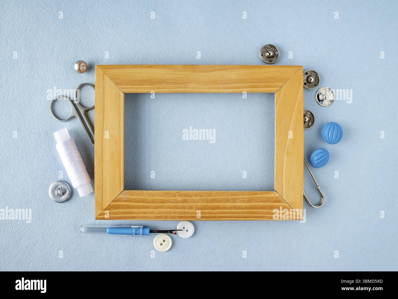 A wooden frame around which are buttons, scissors, threads, a ripper, buttons, sewing accessories Stock Photo