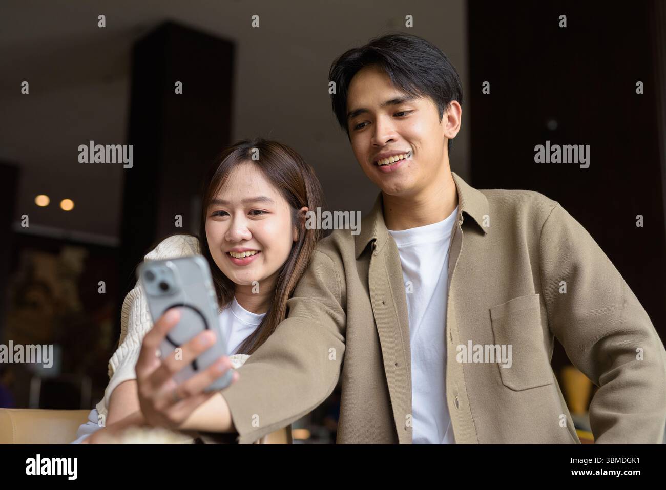 Portrait of a happy young Asian couple taking selfie in cafe with ...