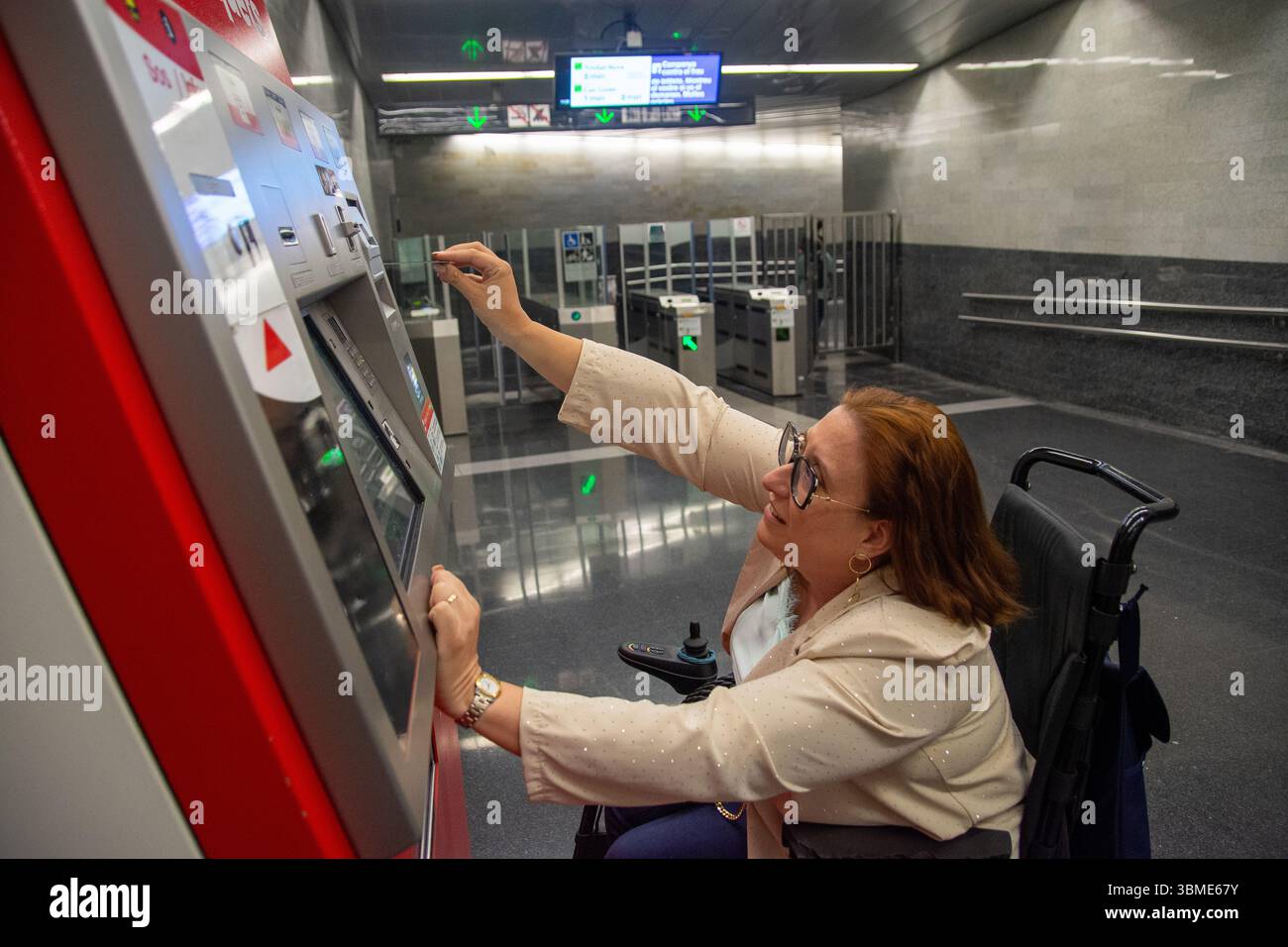 Woman in wheelchair validating ticket at subway station machine ...