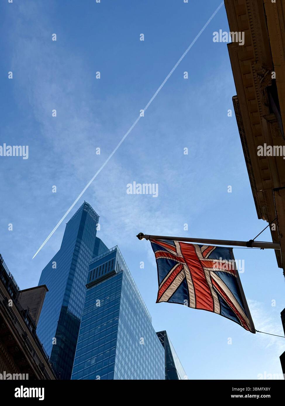 Union flag in City of London against a vivid blue sky with office tower in background - Smartphone Captured Stock Image