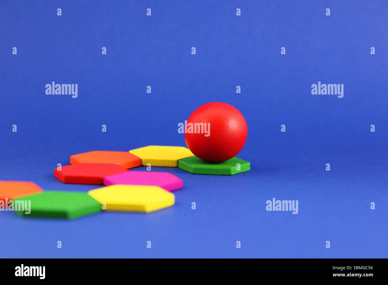 Leading sphere rolls through a path of hexagonal pieces Stock Photo