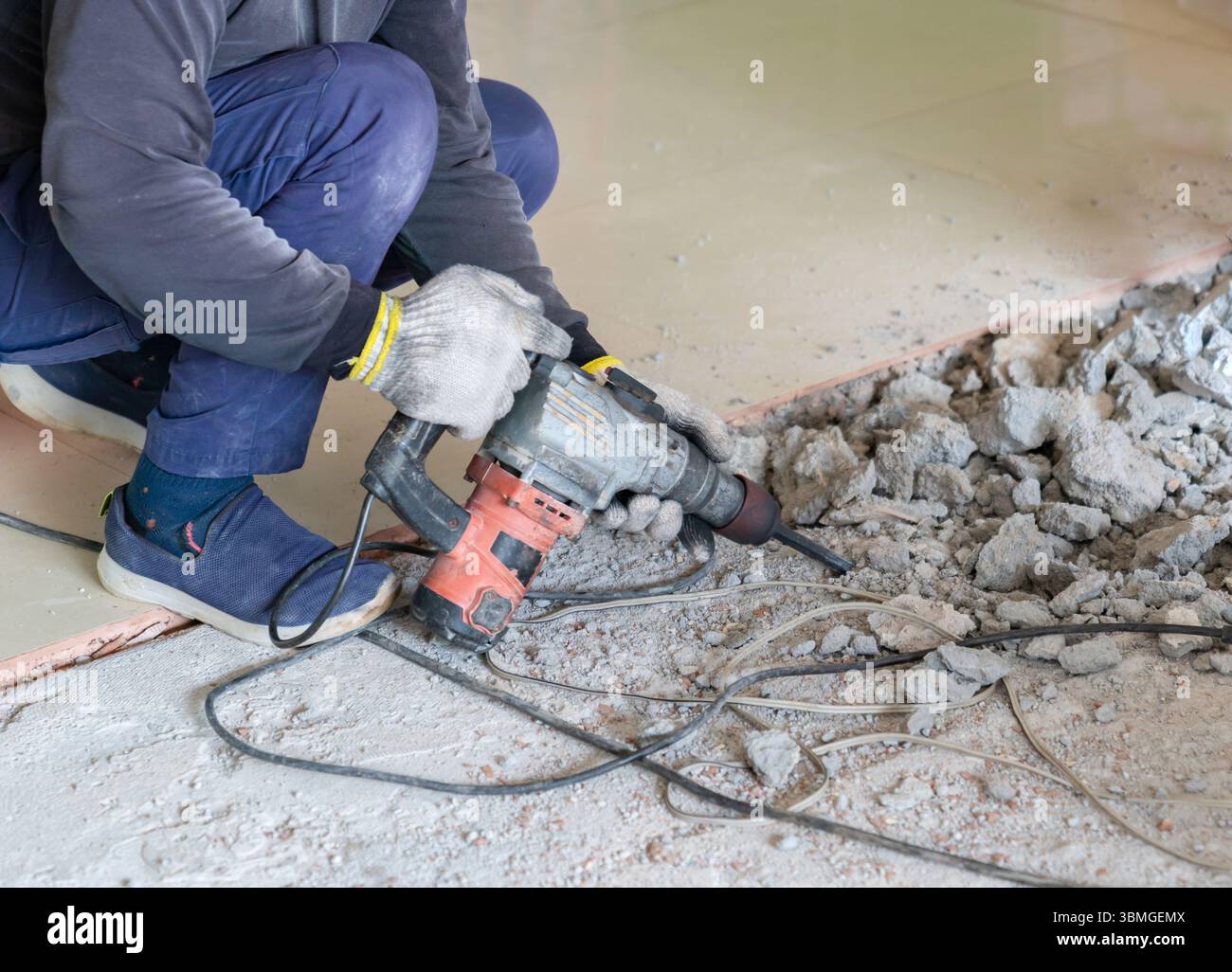 The worker is sitting down to break up the floor with a jackhammer ...