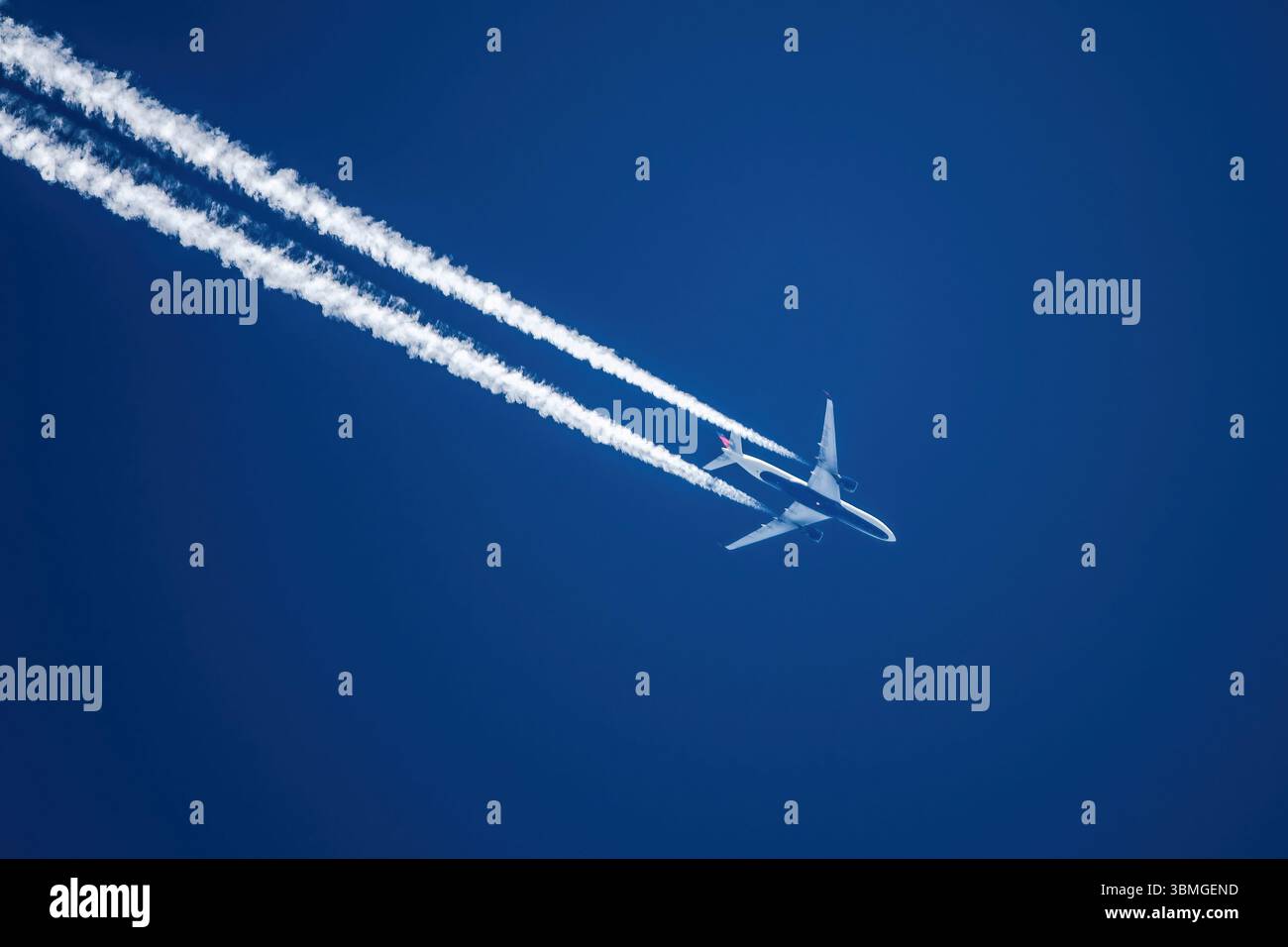 Sharp telephoto close-up of jet plane aircraft with contrails cruising ...