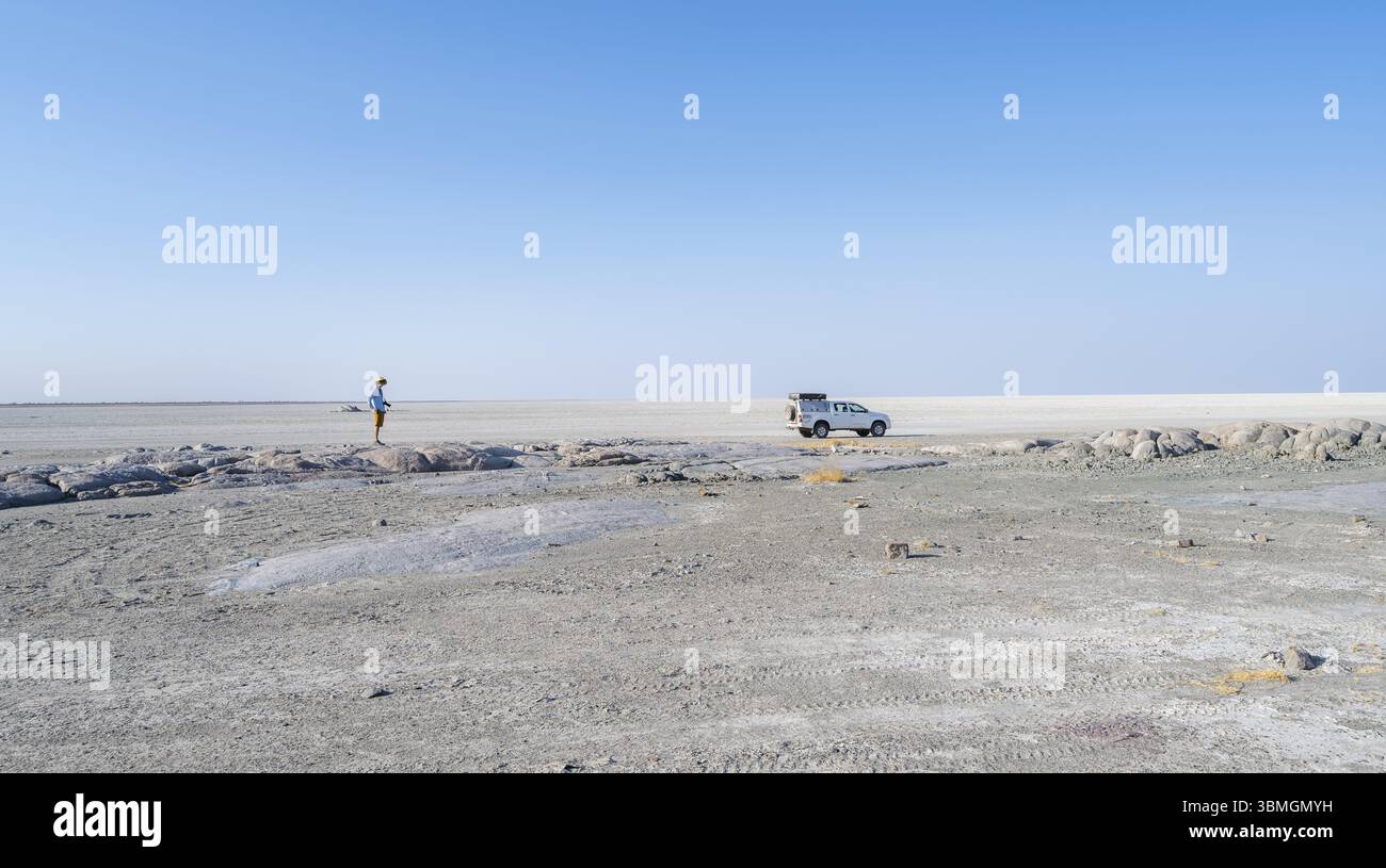Vast white empty landscape on a salt pan, tourist and off-road vehicle ...