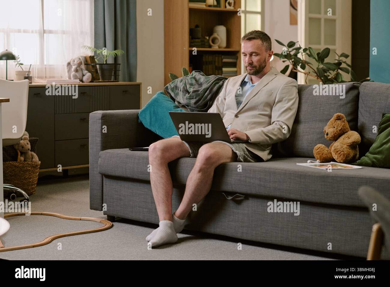 Middle Aged Man Working Remotely Using Laptop While Sitting Indoors Stock Photo