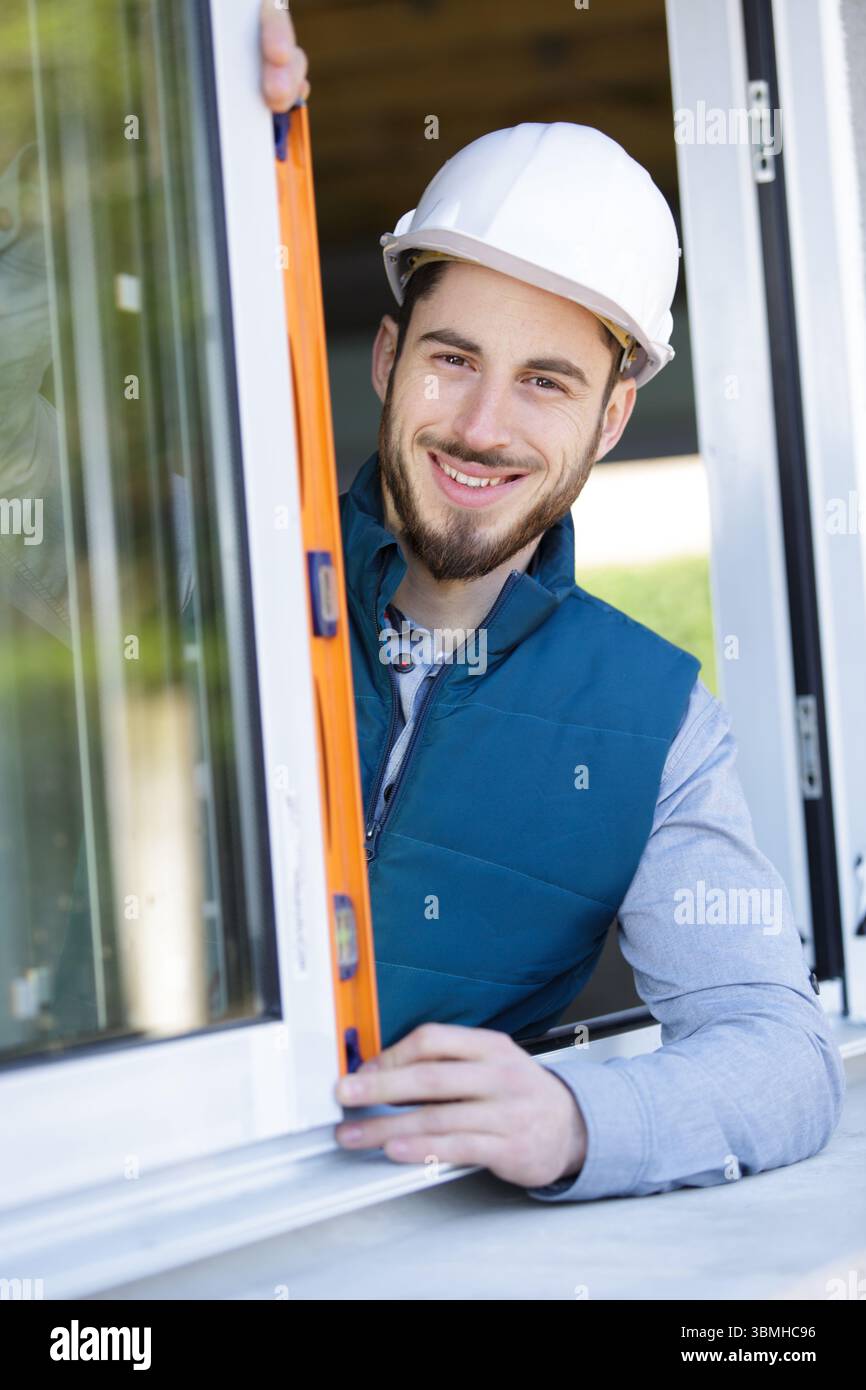 construction worker using bubble level while installing window indoors Stock Photo
