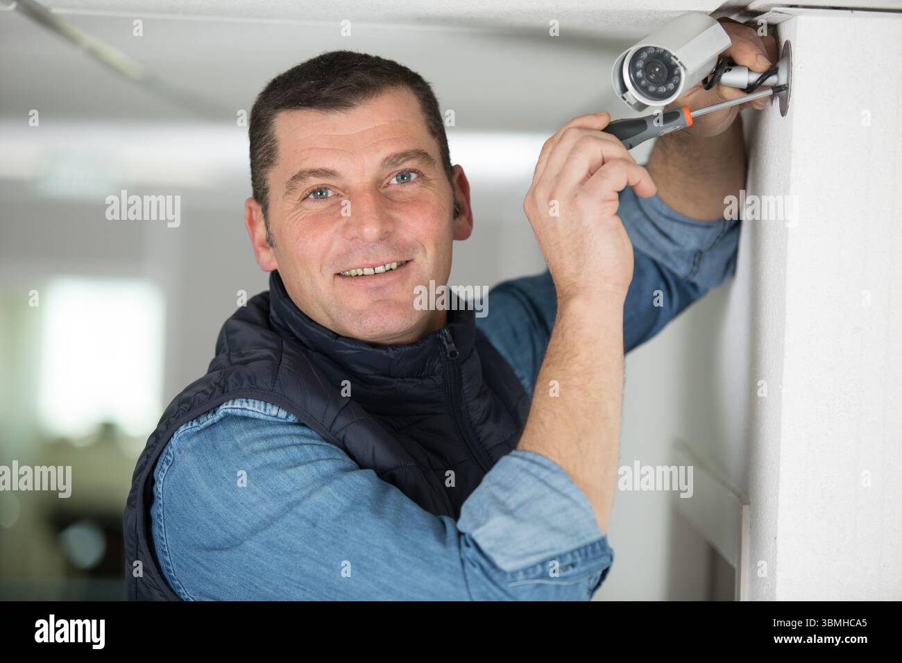 mature technician installing a security camera Stock Photo