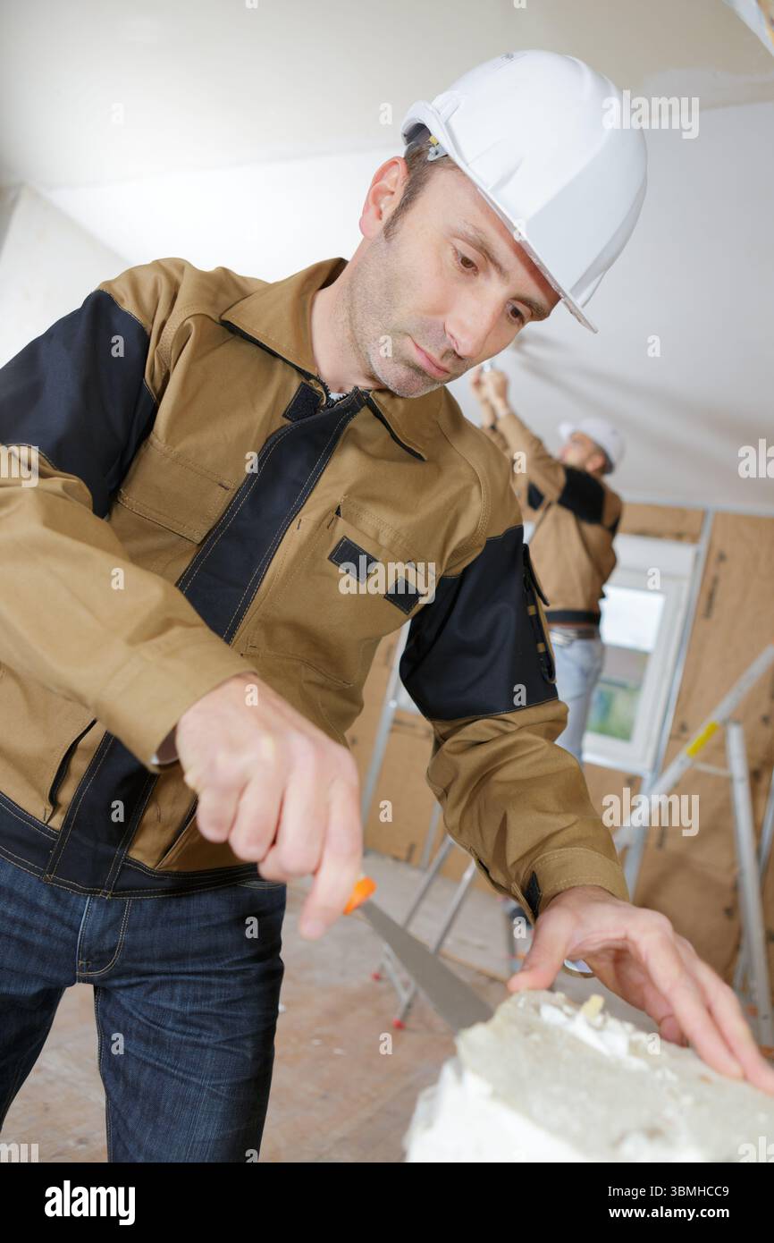 middle age builder pastering cement mortal on the brick wall Stock Photo