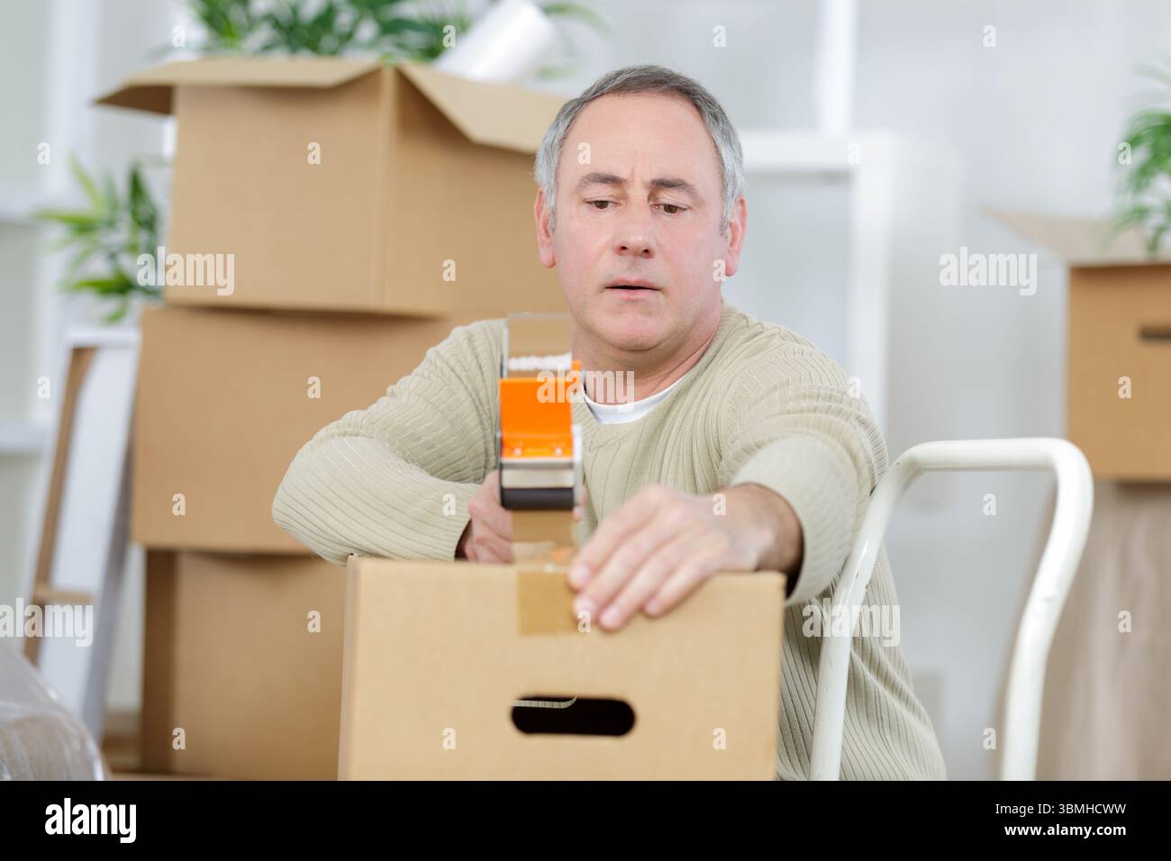 mature man using duct tape for packing stuff in box Stock Photo