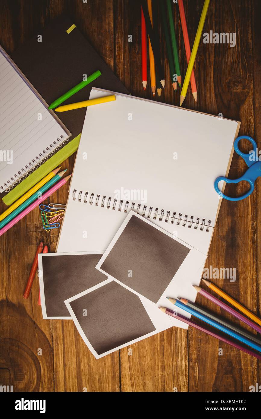 Spiral sketchbook is lying on wooden tabletop in flat design with pencils, scissors, blank prints Stock Photo