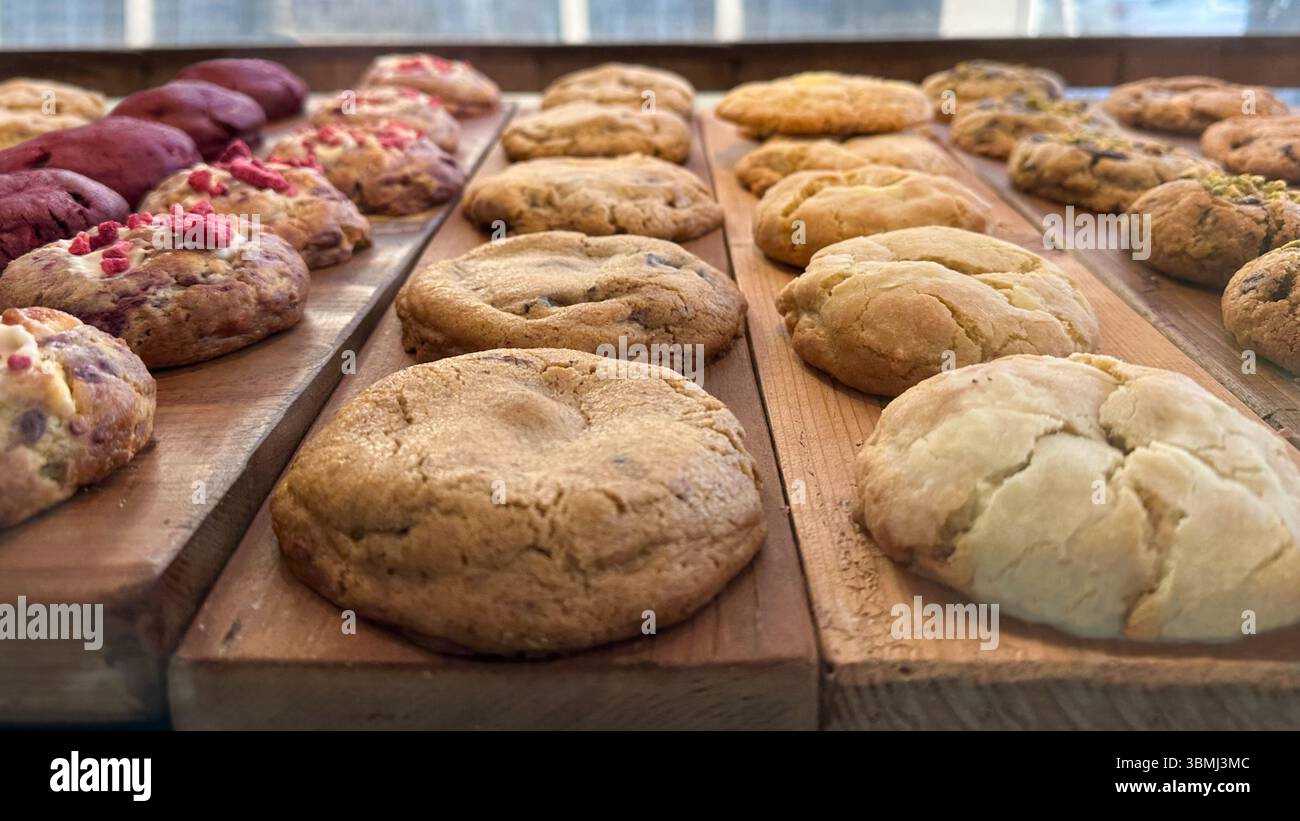 Round, freshly baked cookies with various ingredients, displayed on a rustic wooden surface. Stock Photo