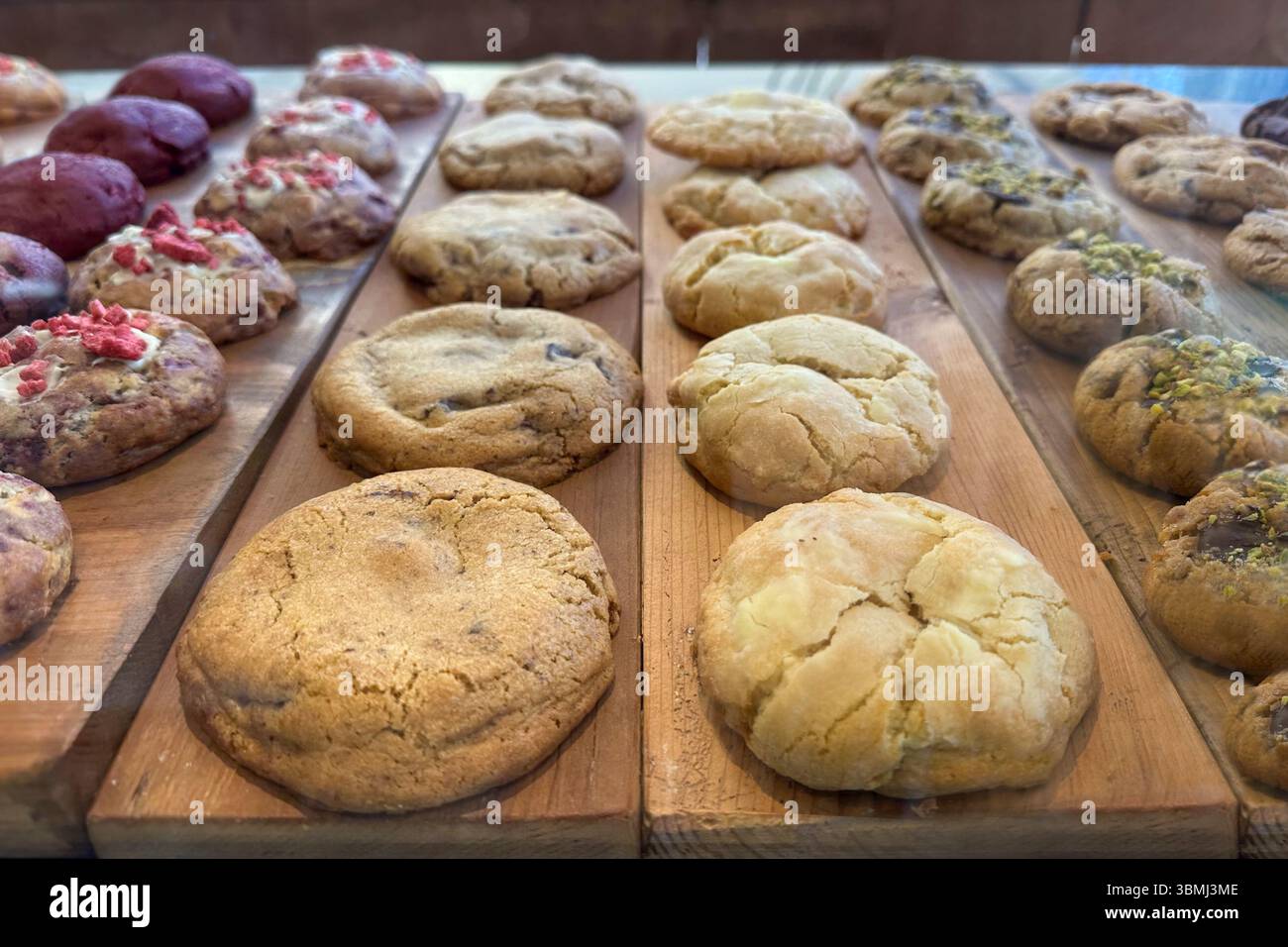 Round, freshly baked cookies with various ingredients, displayed on a rustic wooden surface. Stock Photo