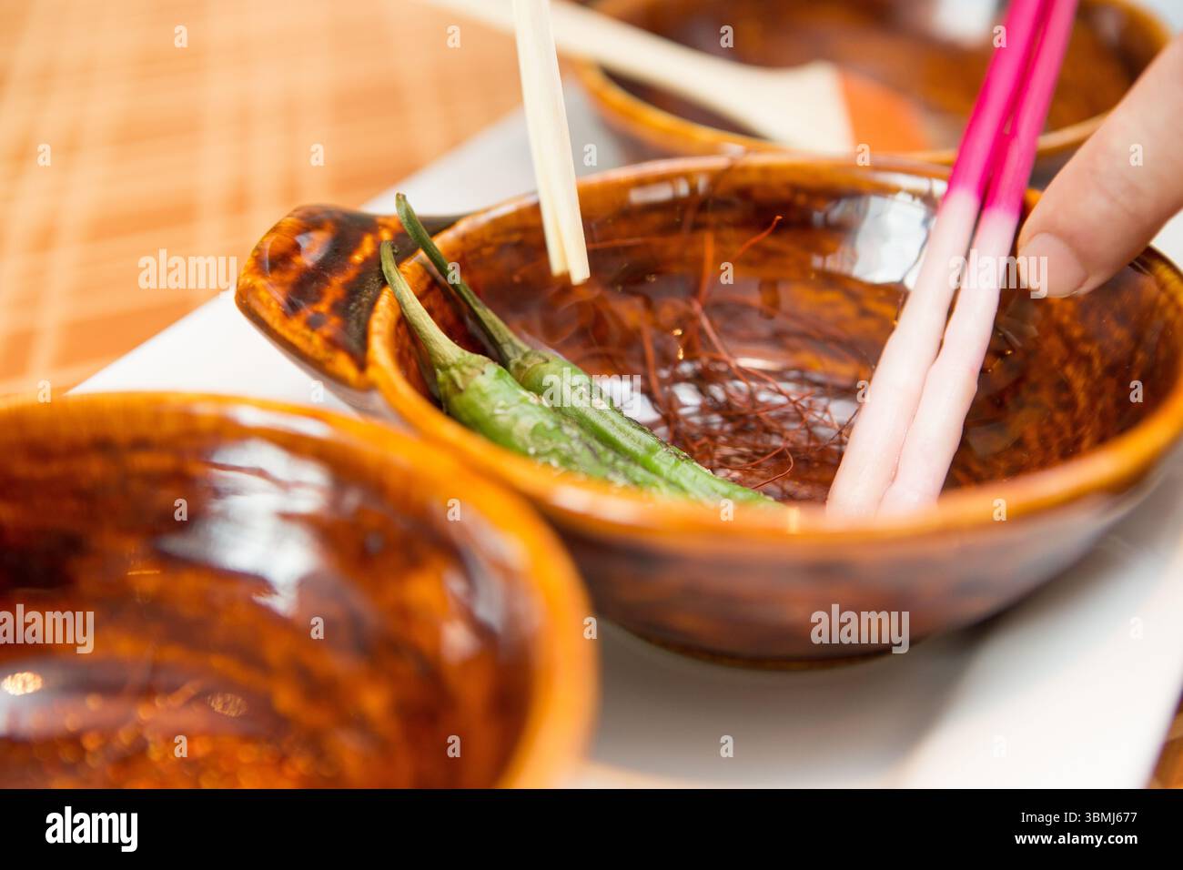 A chef carefully preparing ingredients for a fine dining dish, using traditional ceramic bowls Stock Photo
