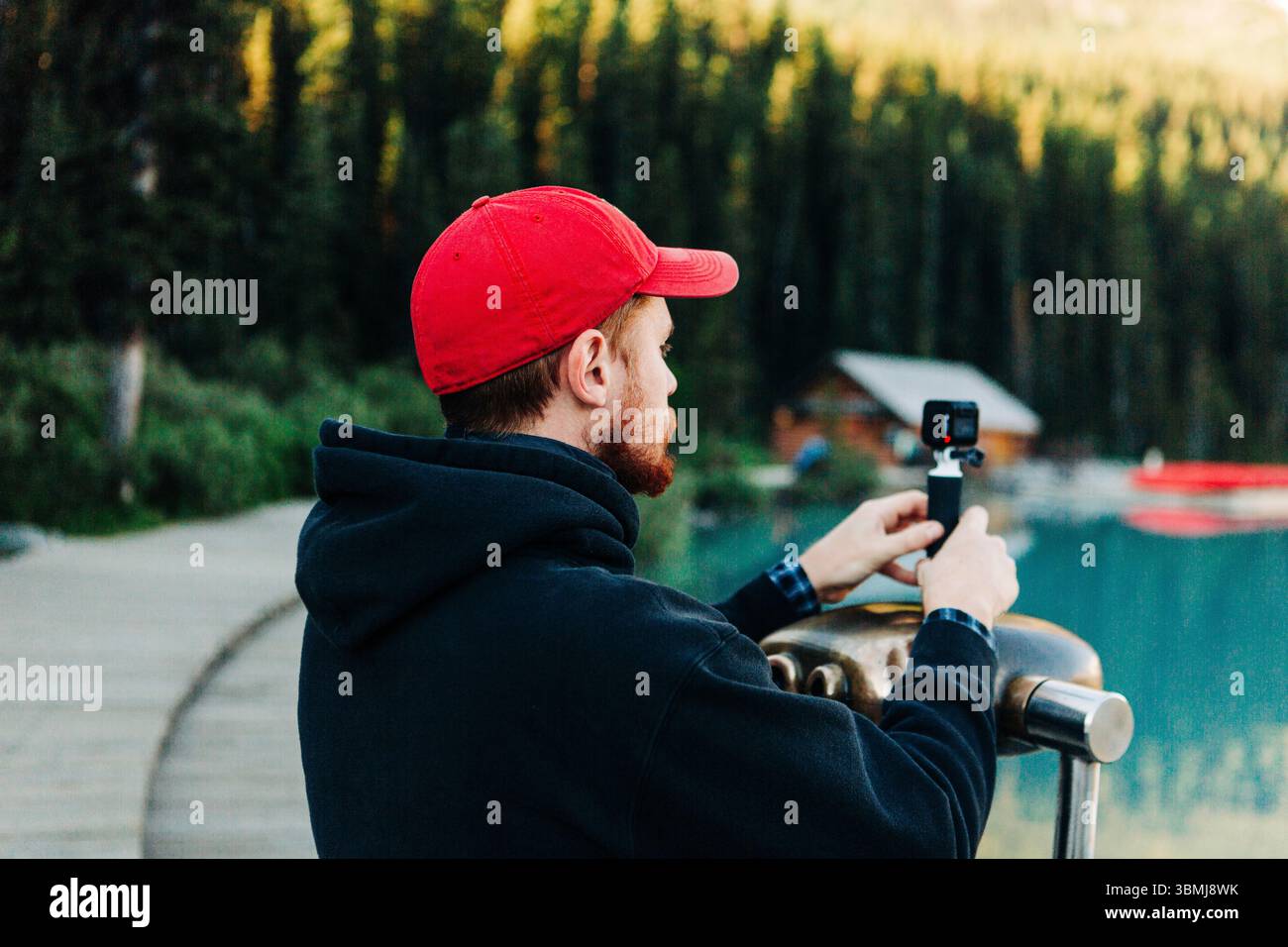 Man filming with action camera at Lake Louise waterfront viewpoint ...