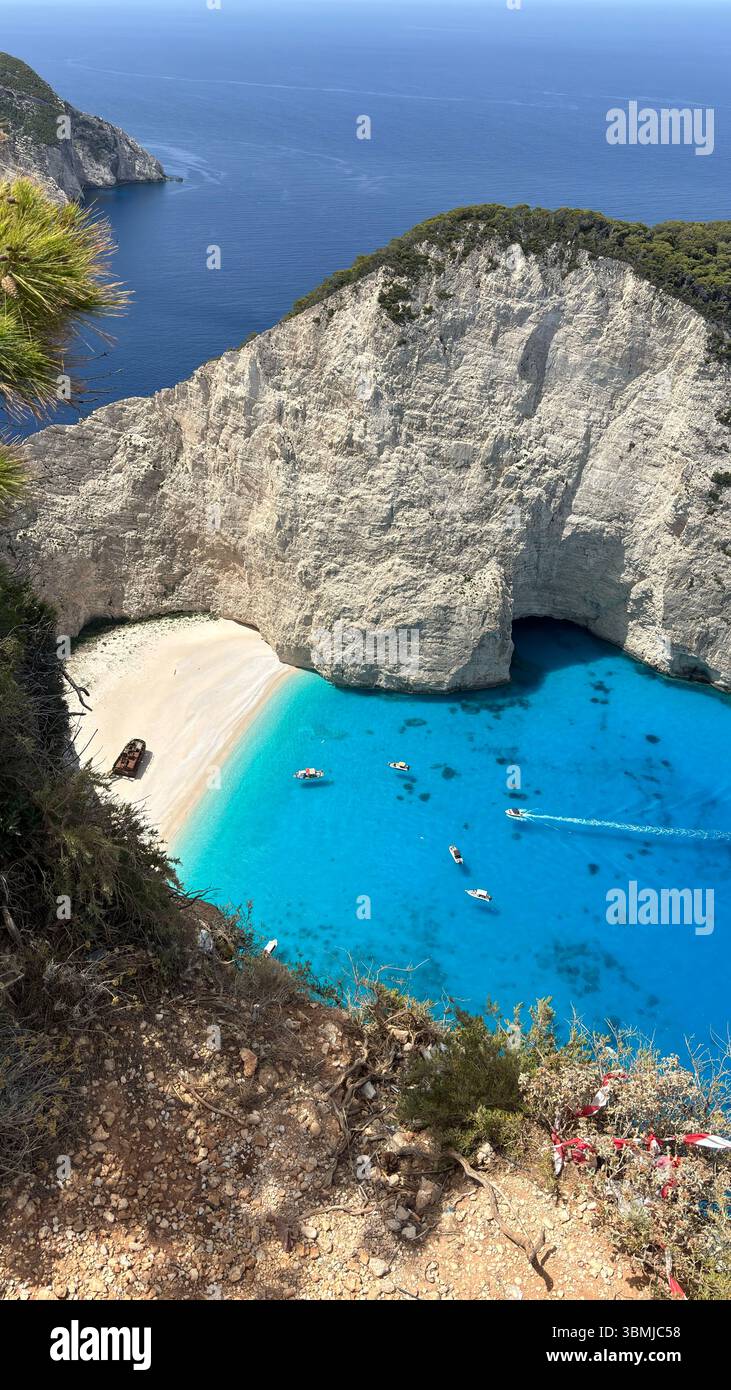 Panoramic view of Navagio Beach (Shipwreck Beach) with turquoise water, dramatic cliffs, and anchored boats on Zakynthos island, Greece. - Smartphone Captured Stock Image