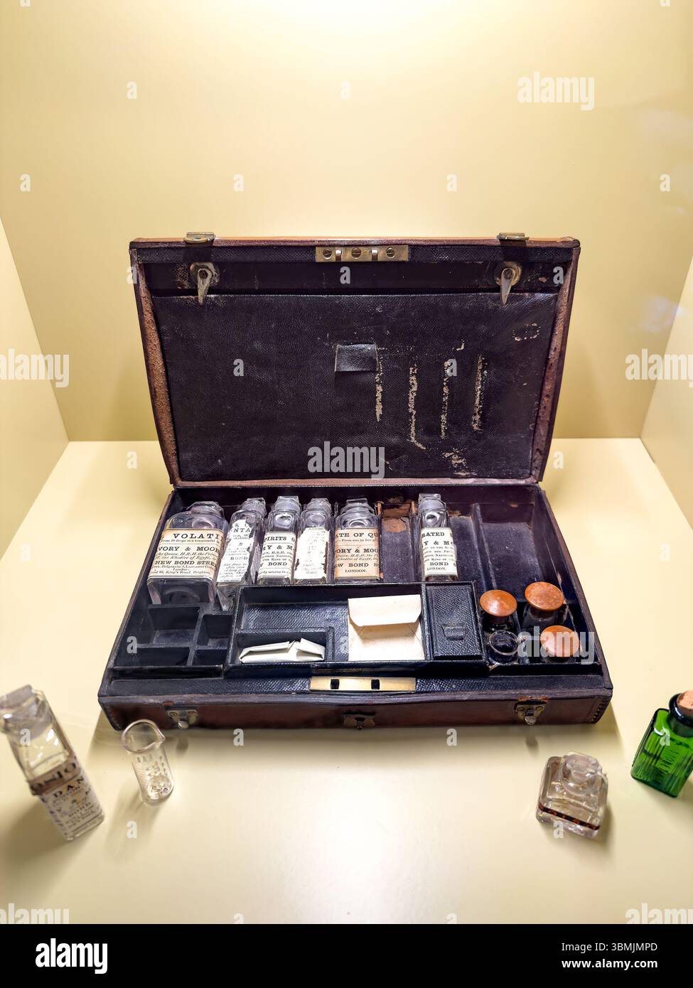 Vintage apothecary kit with glass bottles and cork stoppers displayed on a light brown table in a museum setting - Smartphone Captured Stock Image