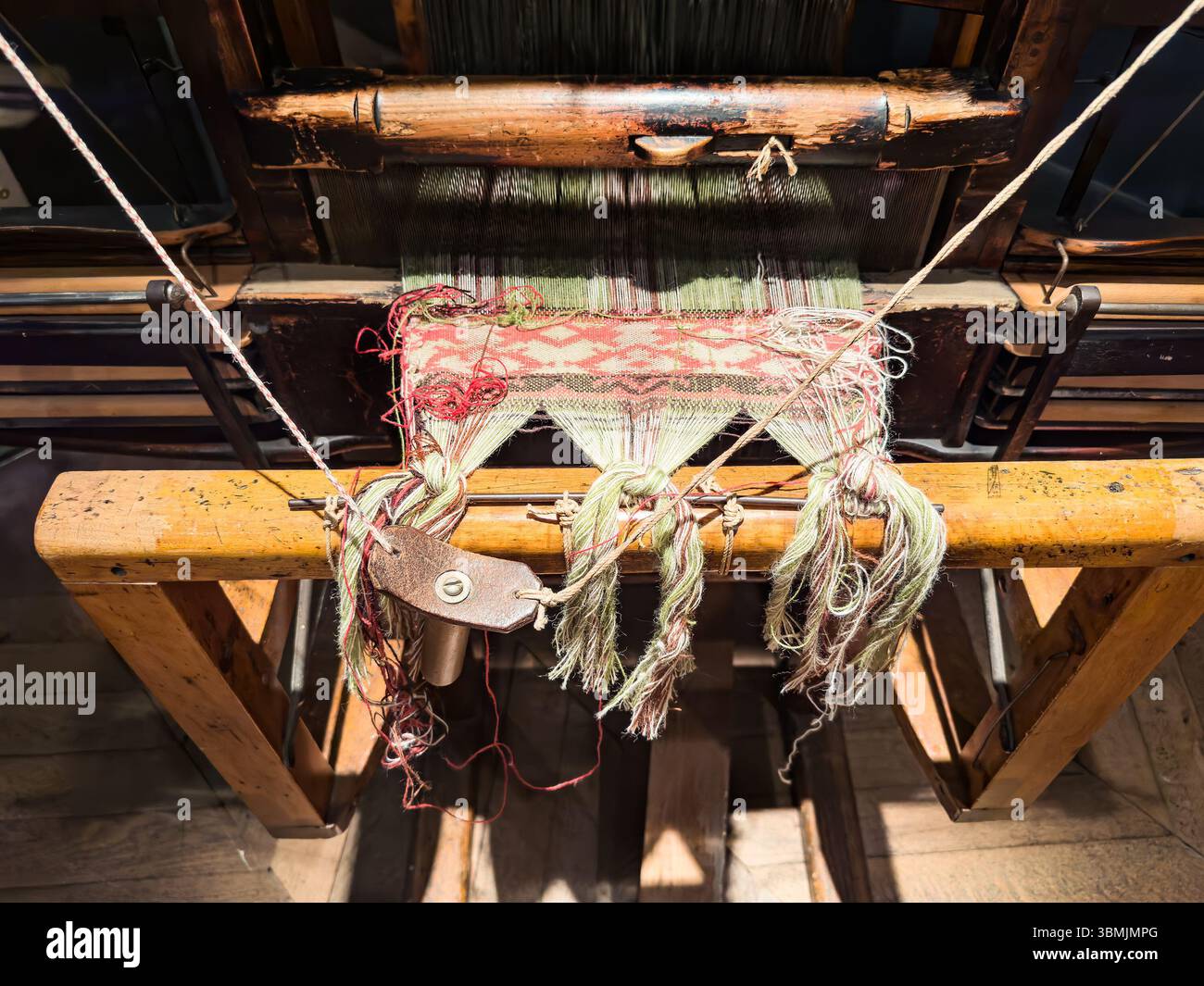 Close-up of a vintage wooden loom showcasing intricate weaving in progress with colorful threads in traditional patterns. - Smartphone Captured Stock Image