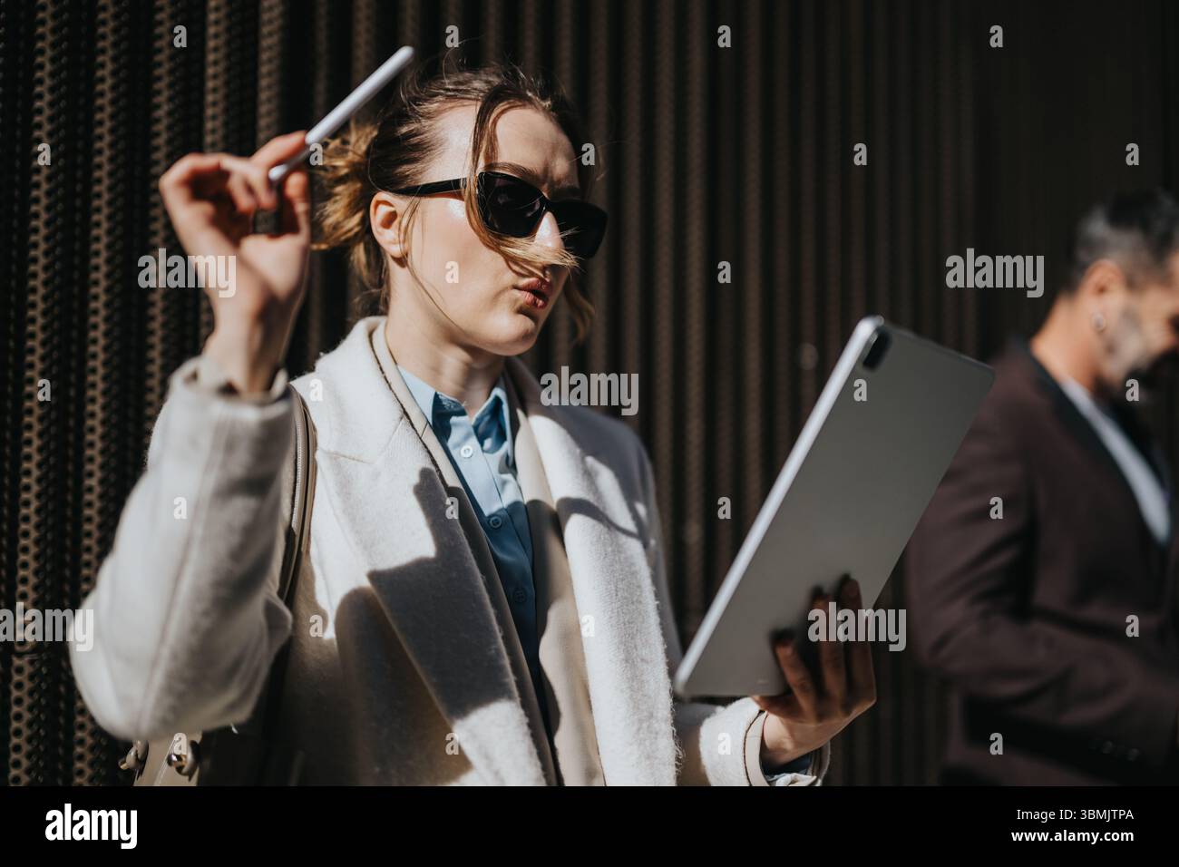 Confident businesswoman analyzing tablet data outdoors while holding a pen Stock Photo