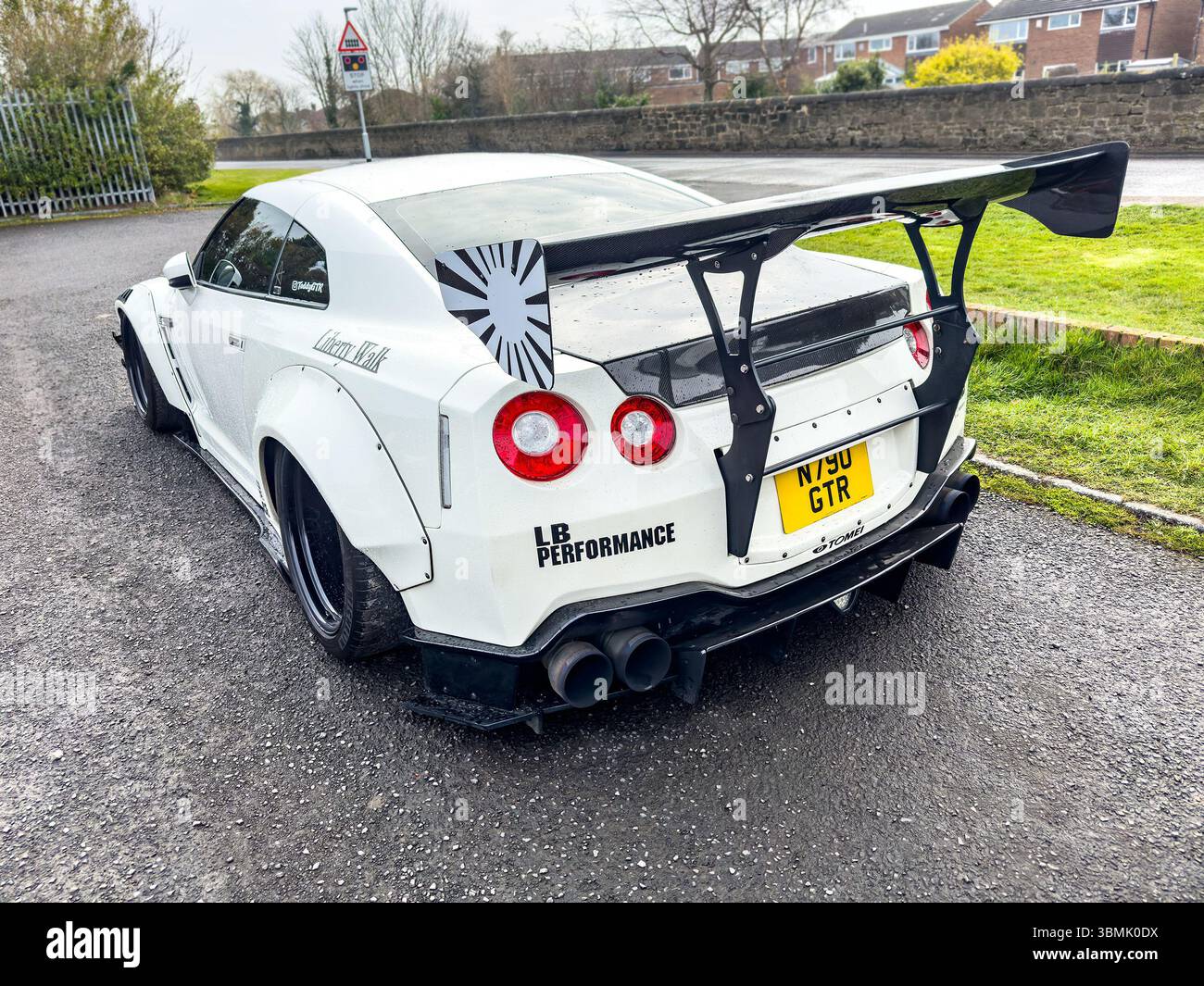 White works nissan GTR sports car with a black hood parked on a wet street, featuring a custom body kit and sleek design elements - Smartphone Captured Stock Image