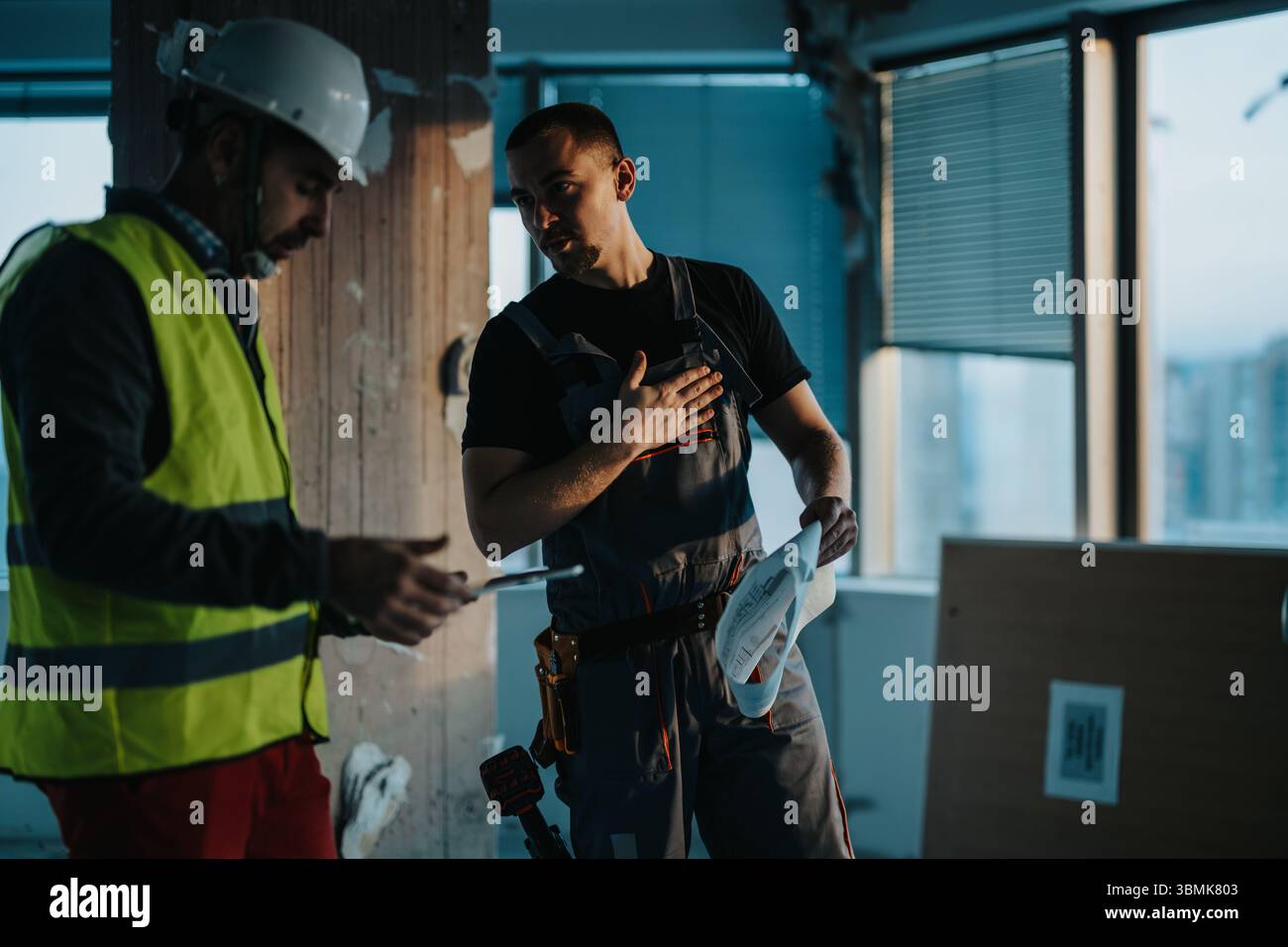 Construction professionals collaborating on a renovation project inside a modern office building Stock Photo