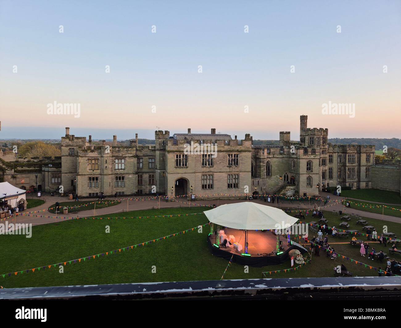 Elevated evening view across the grounds of Warwick Castle during an outdoor public event in Warwick, England. - Smartphone Captured Stock Image