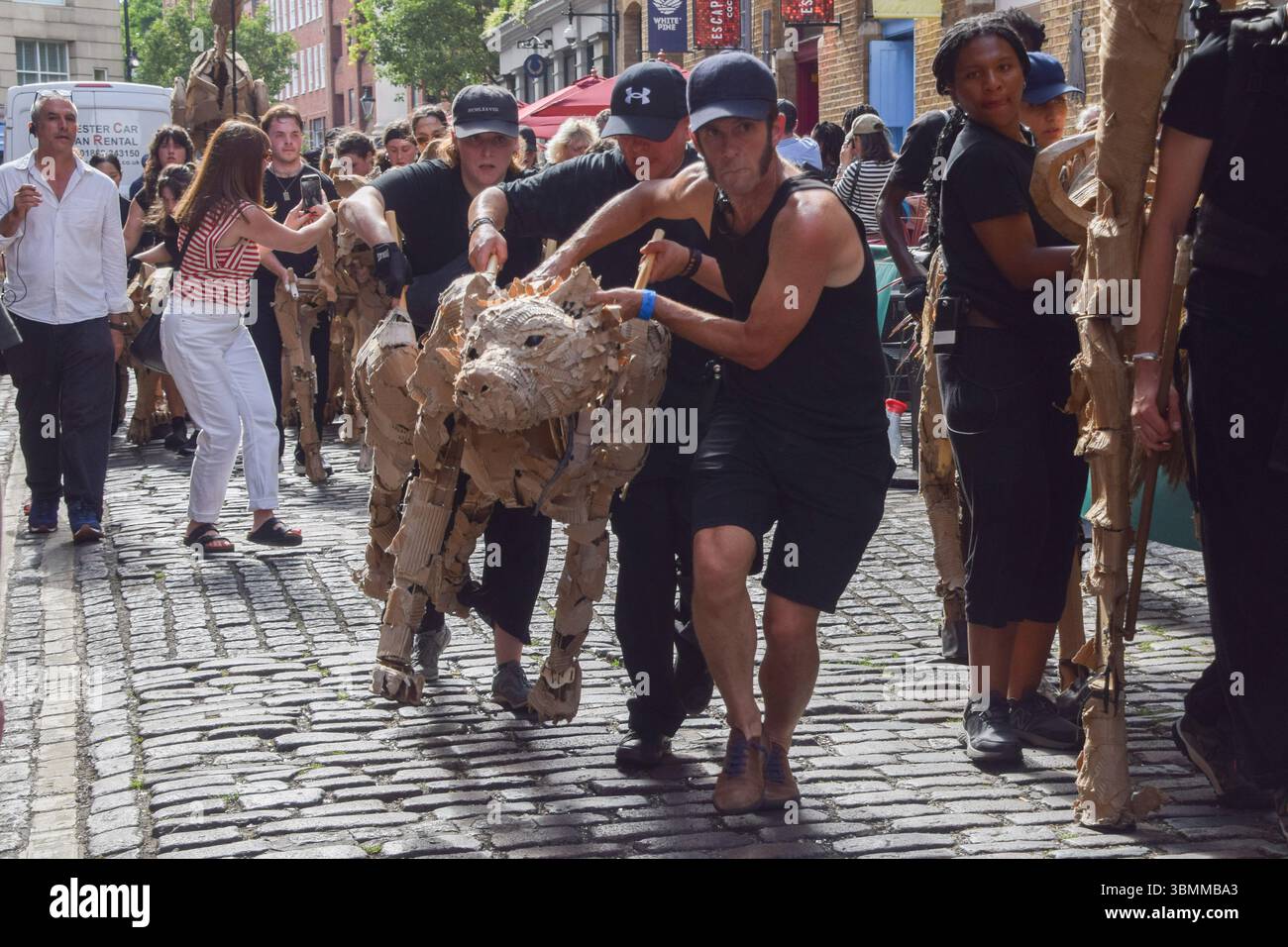 London, UK. 27th June 2025. Puppeteers run with life-size animal ...