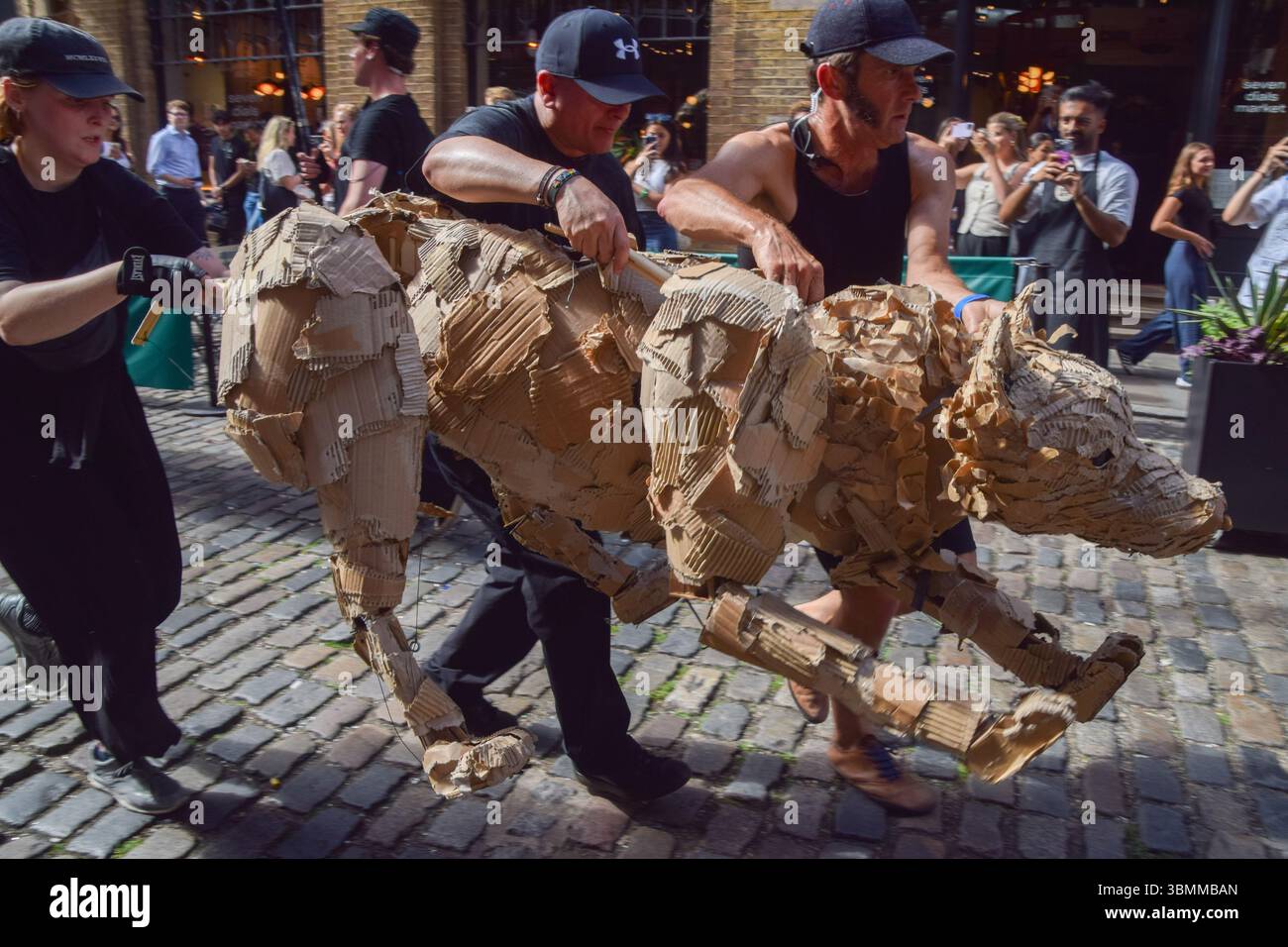 London, UK. 27th June 2025. Puppeteers run with life-size animal ...