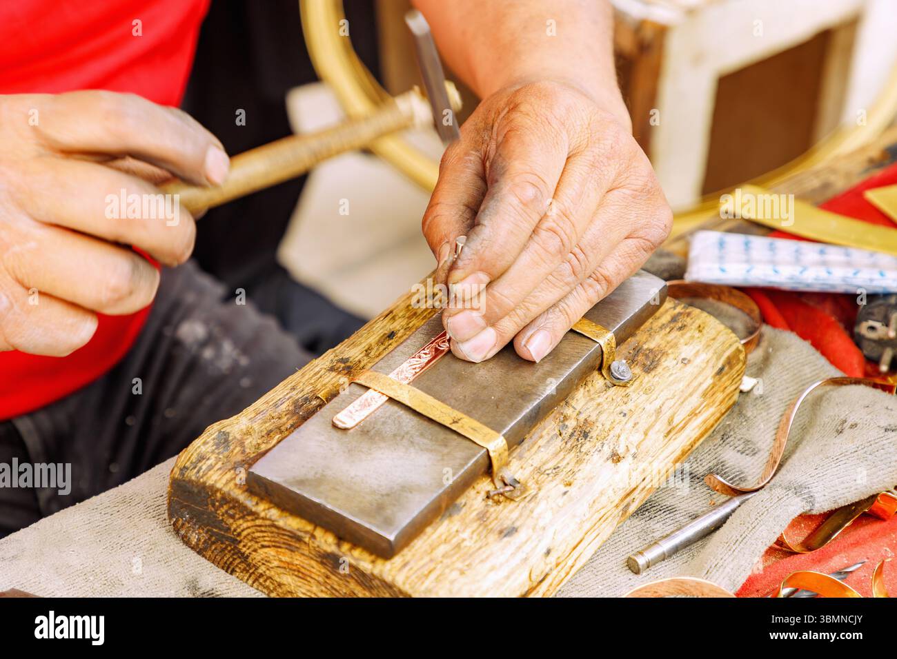 Craftsman engraving a copper bracelet with a traditional engraving tool in the souk in the Medina of Nabeul, Tunisia Stock Photo